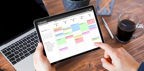 A person using a tablet to view events on their digital calendar.