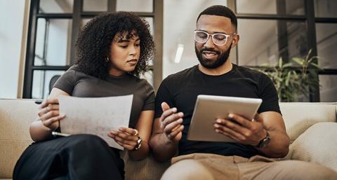 A couple reviewing documents while sitting on their couch.