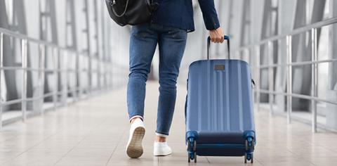 A close up of a person walking down a hallway while rolling luggage