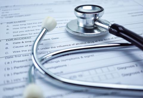 A close up view of a stethoscope laying on top of patient forms.