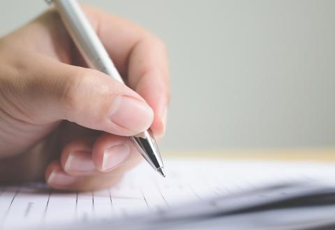 A close up view of a hand filling out documents.