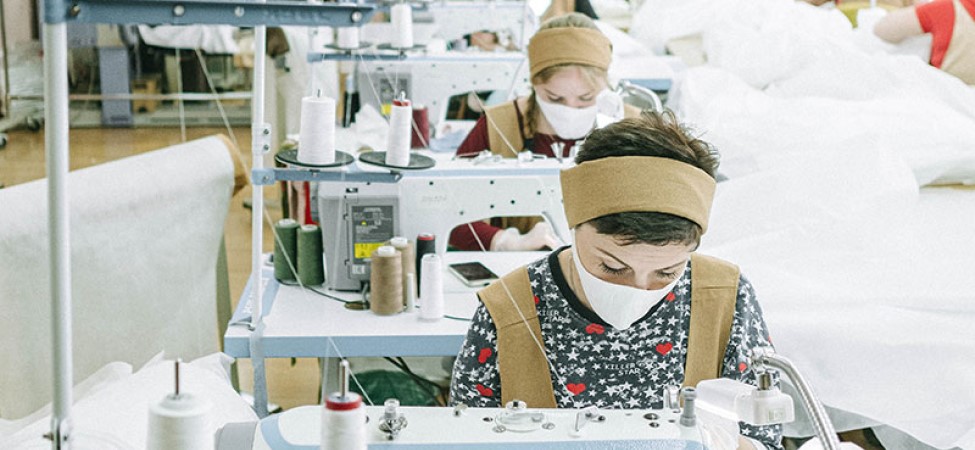 Women wearing white face masks working in a sewing/garment factory