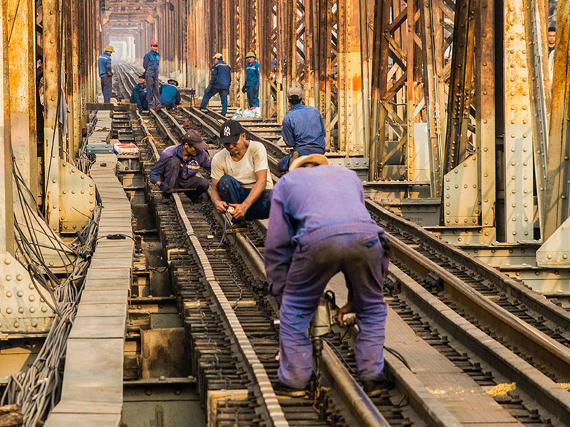 Men in blue jumpsuits working on railroad tracks