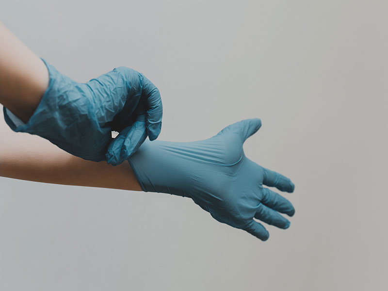 Person putting on blue medical gloves.