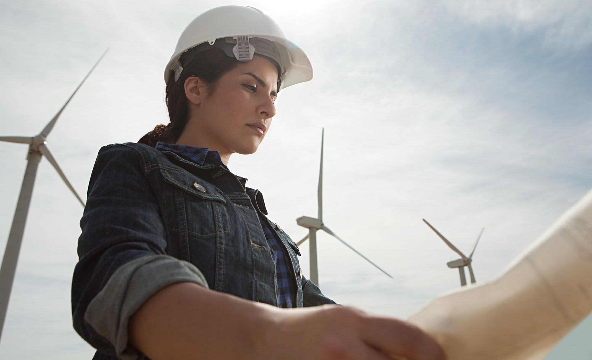 A female engineer on a windfarm looking over site plans.