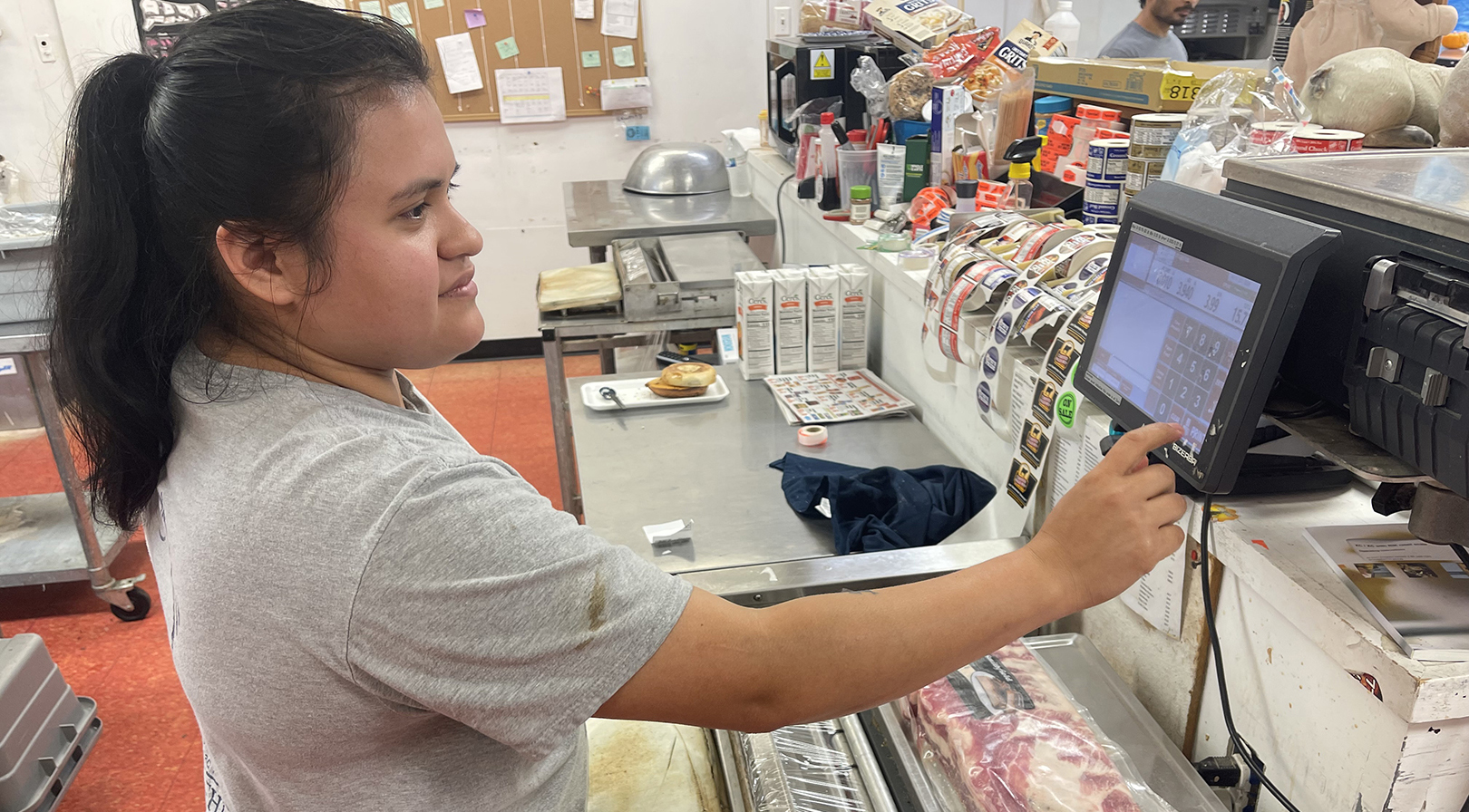 A woman weighing ribs on a scale behind a meat counter