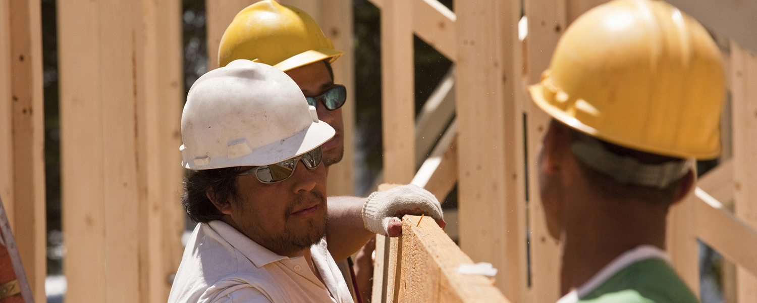 Construction workers lifting a wooden beam while working on a construction site