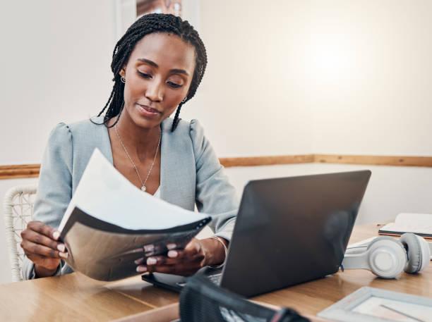 a small business owner reviews a document. An open laptop sits on the table