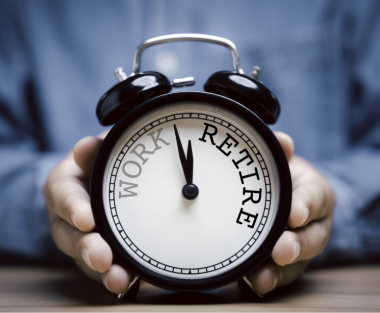 Close-up of hands holding an alarm clock with “work” and “retire” written on the face, pointing towards “retire”.