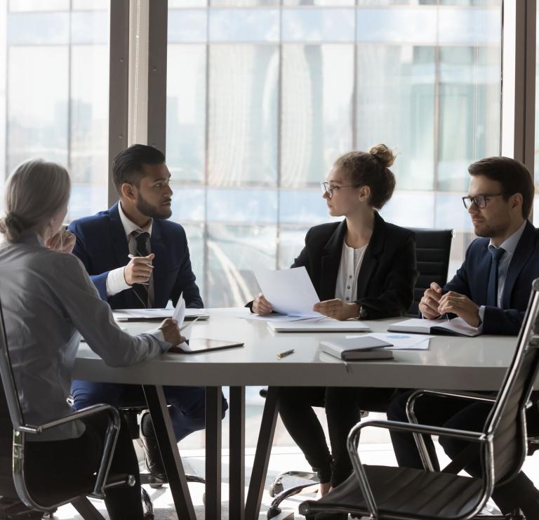 A group of your professionals holding a discussion around a conference table