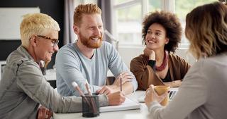 Four coworkers smiling and talking during a team meeting. 