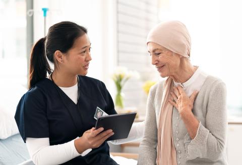 A doctor and a patient discuss and look at information on a tablet in a doctor's office.