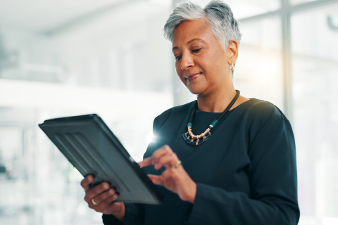 A portrait view of a person holding a tablet and zooming in to a part of the screen.