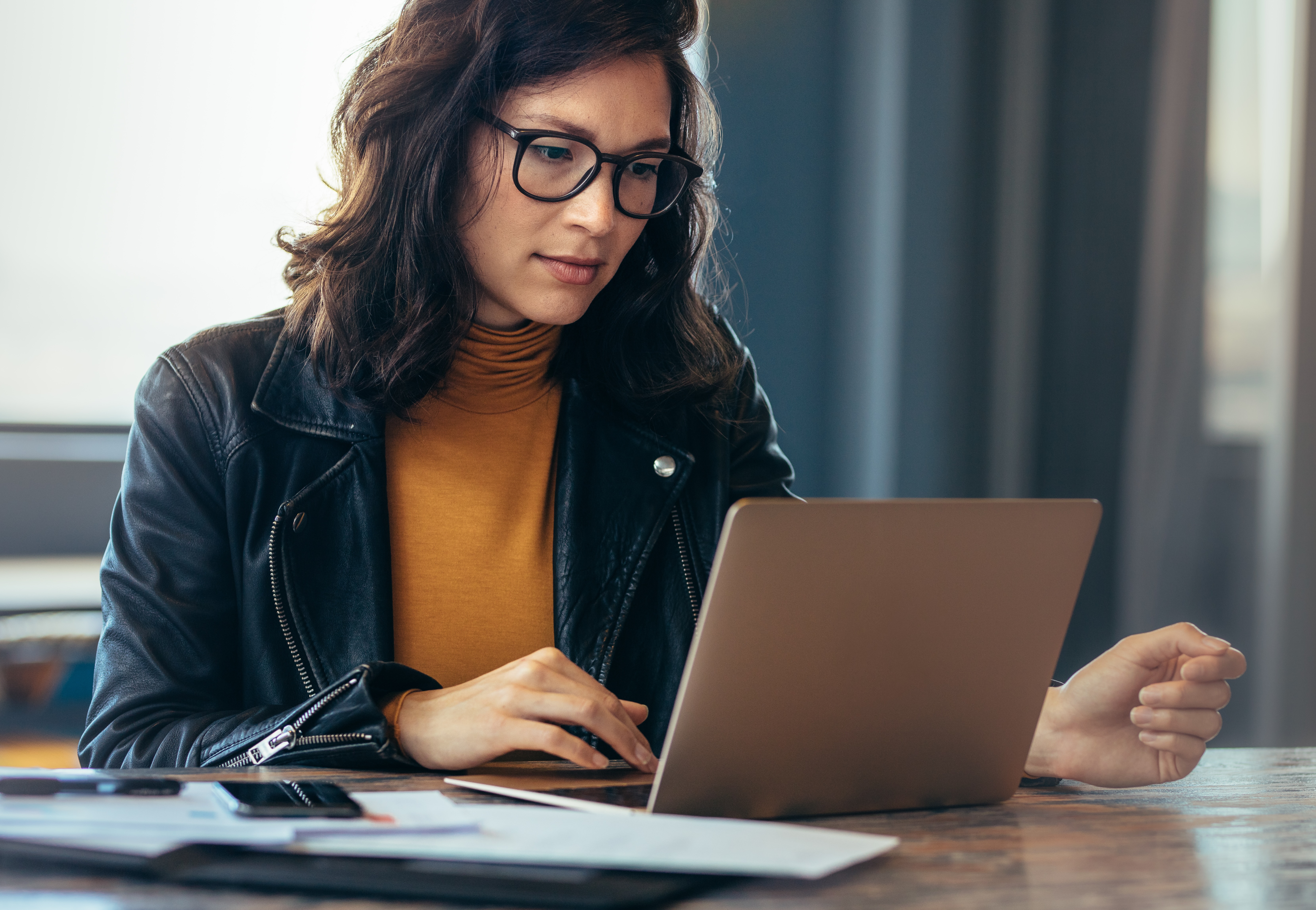 A person sits at a desk as they use their laptop.