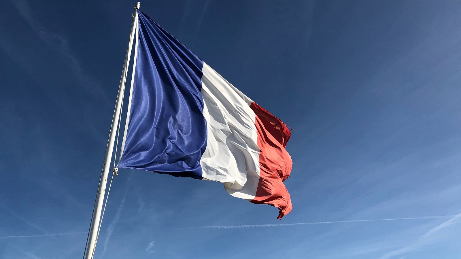 French flag flying on a pole with a blue sky