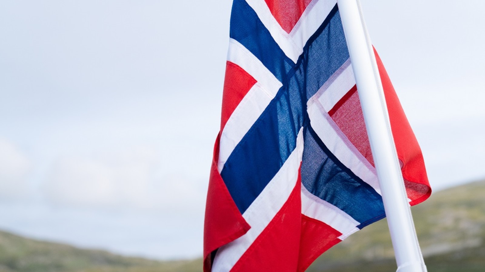 Norweigen flag with green mountains and houses in the background