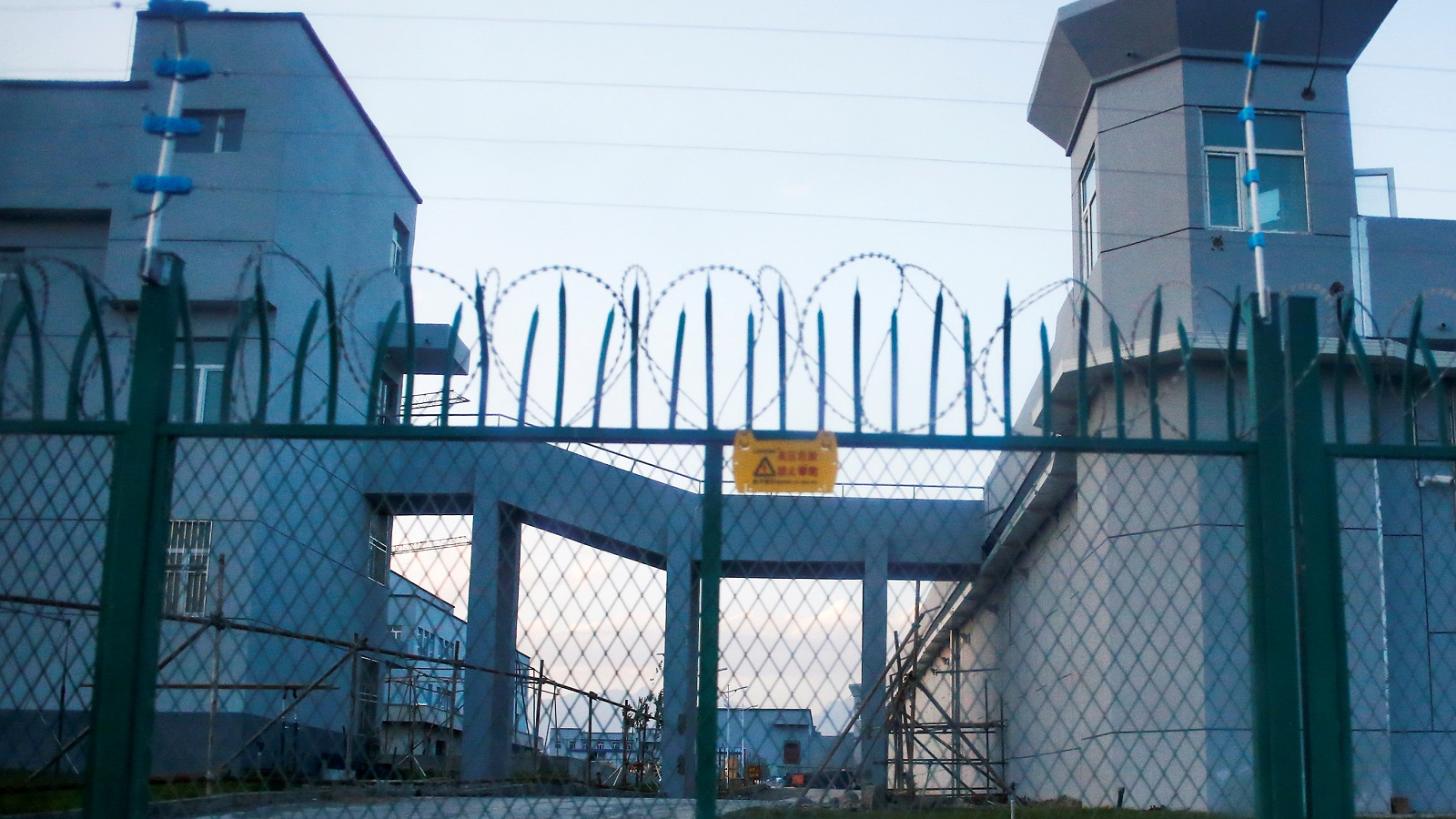Large gates with barbed wire leading into a detention camp