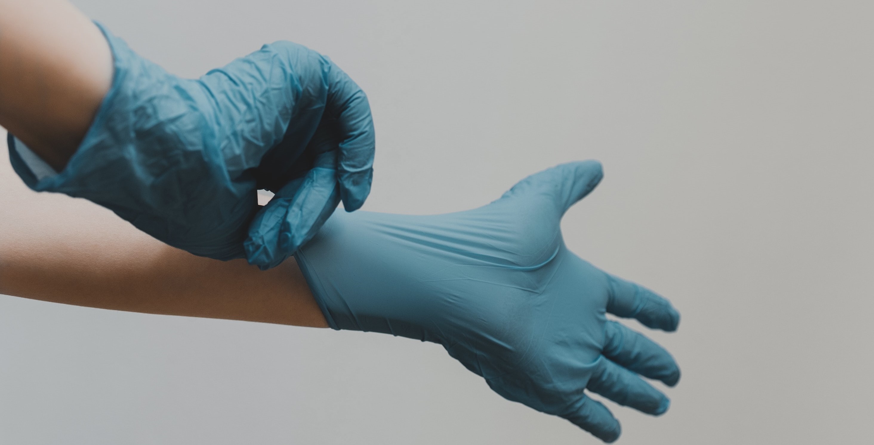 Person putting on blue medical gloves