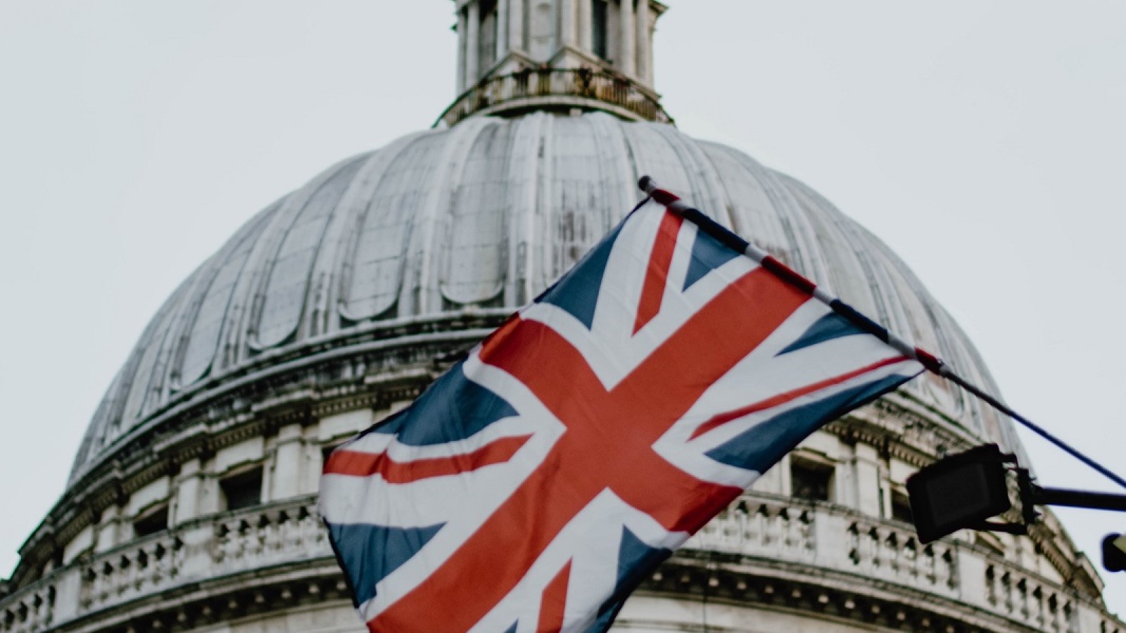 British flag Union Jack flying on a pole next to a large building with a dome
