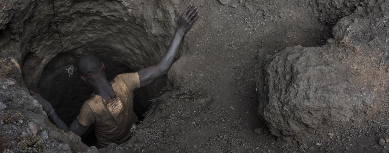 Boy climbing down into hole in the ground to mine cobalt.