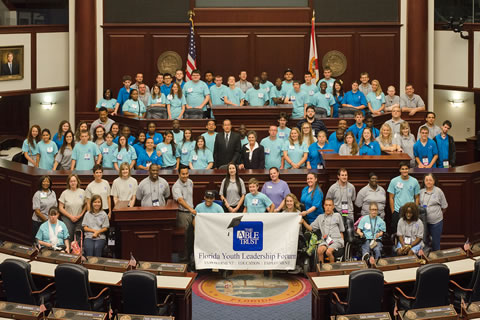 Image of a large group of students sitting on raised podiums in a legislative chamber