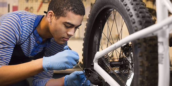 A teenage boy working in a bicycle repair shop.