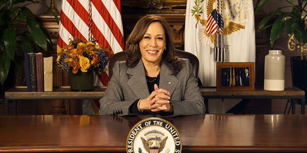 Vice President Kamala Harris sits at a desk with the Vice Presidential seal.