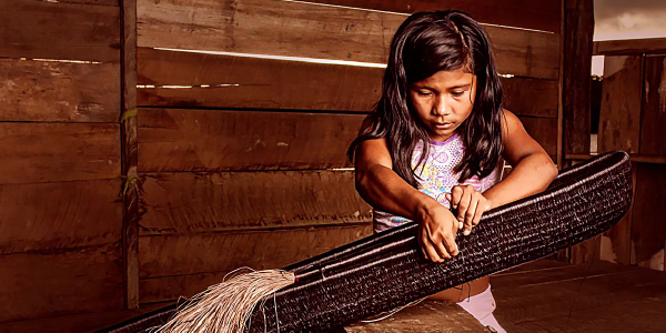 A young girl weaves a basket. 