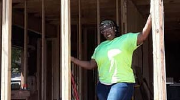 A woman poses in the doorway of a house under construction.