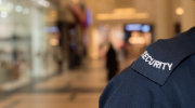 Close-up of the shoulder of a security guard in a mall. A shoulder patch reads security.