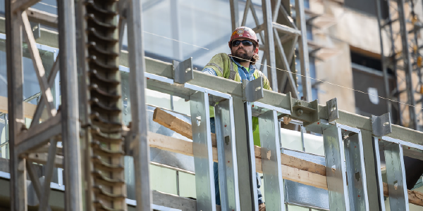 A construction worker on a scaffold takes a break to listen to a safety presentation. 