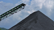 A mound of coal, with a conveyor in the background.
