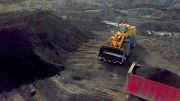 A hydraulic mining shovel near an enormous pile of coal.