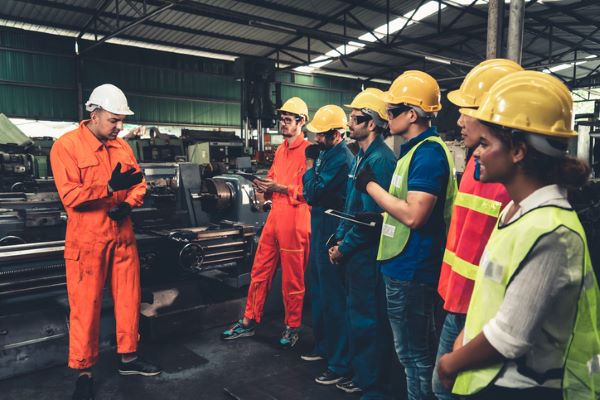 A group of workers in safety gear stands for a training presentation.