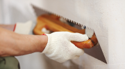 Close-up shot of a worker applying plaster to a wall.