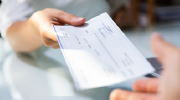 Close-up shot of a person handing a check to another person. 