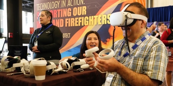 A man wears a Virtual Reality headset while holding two hand controllers. 