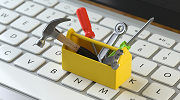 A tiny toolbox sits on a computer keyboard.