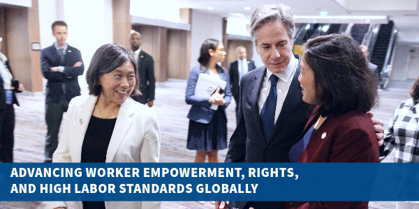 Acting Secretary Su, Secretary Blinken and U.S. Trade Rep. Katherine Tai talk while walking through a hotel lobby. They are surrounded by staff. Text reads: “Advancing Worker Empowerment, Rights, and High Labor Standards Globally.” 
