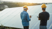 Two men in hardhats examine a solar panel.