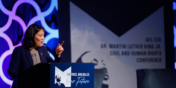 Acting Secretary Su speaks at a podium. A poster behind her reads AFL-CIO Dr. Martin Luther King Jr. Civil and Human Rights Conference.