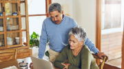 An older couple looks at a laptop. 