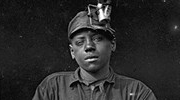 1908 photo of a Black miner wearing an early headlamp and looking directly at the camera. Library of Congress photo by Lewis Hine.
