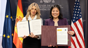 Acting Secretary Su and Yolanda Diaz each hold up a copy of the joint statement they signed.