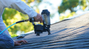 A roofer uses a nail gun to affix tiles to a roof. 