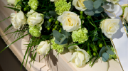 A tasteful arrangement of white flowers sits atop an elegant wooden coffin. 