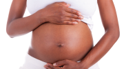 A pregnant Black woman holding her stomach.