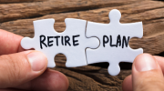 Two white puzzle pieces being held together with the words "retire" and "plan" written in black on the two pieces. 