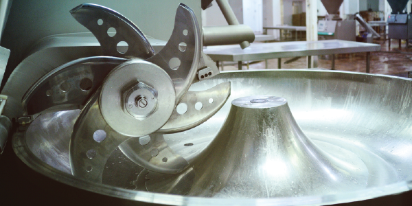 An industrial mincer with six sharp blades in a meat processing facility.