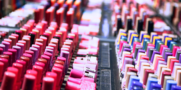 An array of colorful nail polish bottles arranged in rows on a store display, showcasing a gradient of shades from red to blue. 